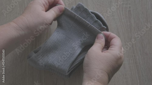 Female hands check cotton socks for quality, meticulous inspection footwear, Elastic bands and fabric texture. Diabetic-friendly apparel. Clothing purchase