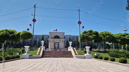 CHISINAU, MOLDOVA - JUNE 20, 2025 Triumphal Arch as popular historical landmark of the capital with the Moldovan Government House in the background