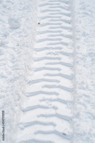 Close-up of tractor tracks on snow-covered cobblestones. Tire tracks on a winter road.