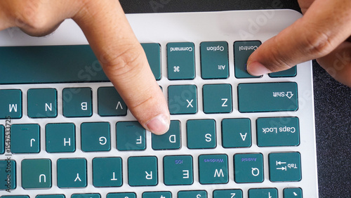 Finger pressing control and D or ctrl + D shortcut keys on a green wireless computer keyboard isolated on black background