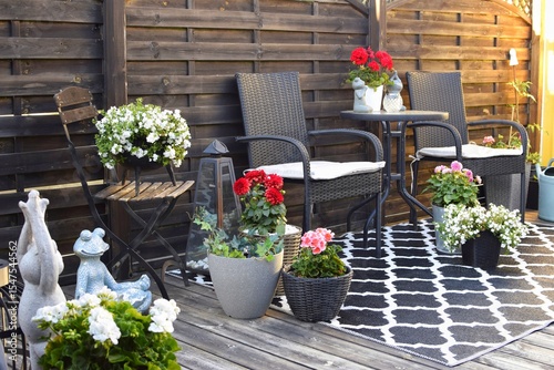 Two wicker chairs with a table, flowers in pots. A place to rest and relax.