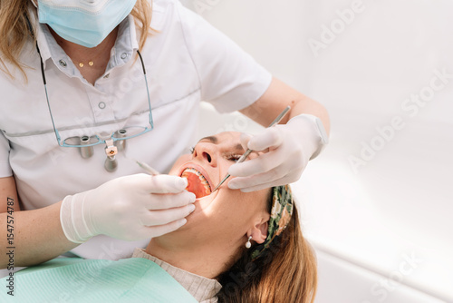 Dentist examining patient's teeth with dental instruments in clinic