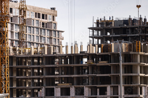 Construction site background. Hoisting cranes and new multi-storey buildings. Industrial background.