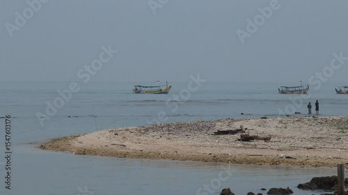 Fishing boats passing through shallow waters on a tropical beach