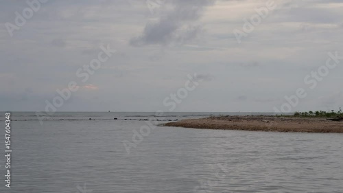 Zoom out of Shallow water beaches are eroded, remaining coral rocks and a few retaining plants such as mangroves.