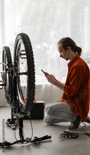 man repairing bicycle at home uses smartphone communicates with artificial intelligence asks for help in repairing and maintaining bike