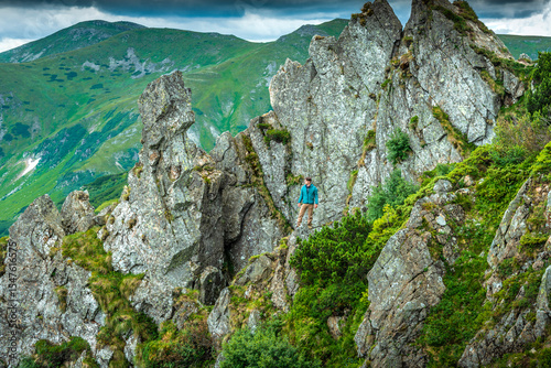Hiker standing on rocky ridge in the Carpathian mountains, looking at scenic landscape. Alpine hiking and mountain adventure concept