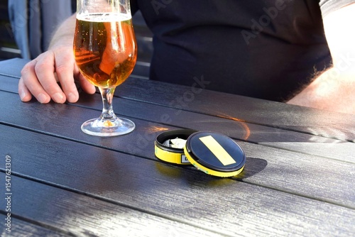 A box of snus pads and a glass of beer on the table.