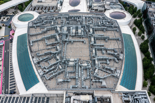 Top-down view of urban rooftop structure with visible HVAC ventilation ducts and curved skylights. architectural symmetry in commercial district photo