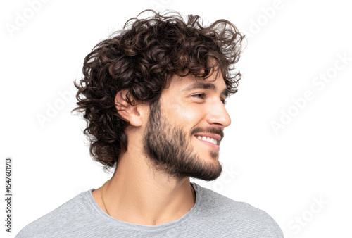 A young man with curly hair and a beard smiling confidently while looking to the side against a plain background. showcasing a relaxed and approachable demeanor suitable for lifestyle imagery