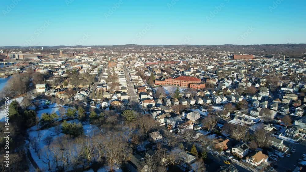 Sunny day in American town of Lawrence , Massachusetts. Aerial wide shot. Frozen Merrimack River in center of city. Neighborhood with houses and homes in winter season. Wetherbee school with red brick Sunny day in American town of Lawrence , Massachusetts. Aerial wide shot. Frozen Merrimack River in center of city. Neighborhood with houses and homes in winter season. Wetherbee school with red brick