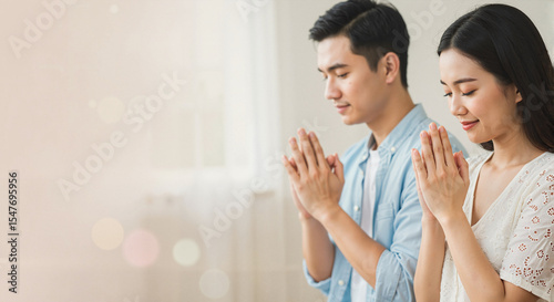 Young couple holding hands in prayer in a bright indoor setting  