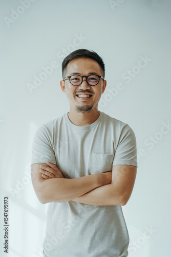 Portrait of a smiling asian man with glasses and arms crossed