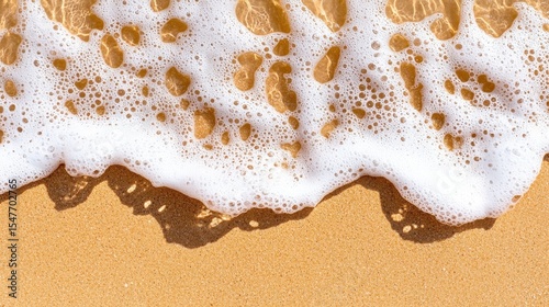 White Ocean Foam on Sandy Beach Close up view of sea waves receding leaving white foam on golden sand