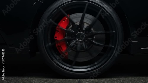 Car wheel spinning with red brake caliper, motion blur effect, automotive performance video