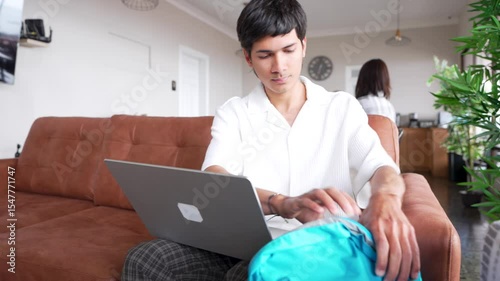 Latin American digital nomad freelancer packing laptop in backpack after finishing work on sofa