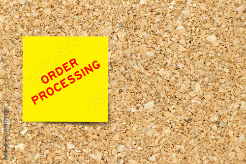 Yellow note paper with word order processing on cork board background with copy space