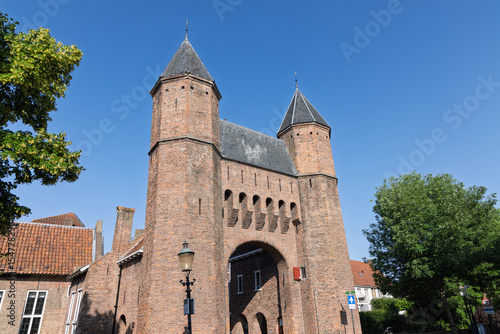 Imposing Kamperbinnenpoort gate in Amersfoort, Netherlands, stands tall against a clear blue sky, showcasing its historic brickwork and iconic towers.
