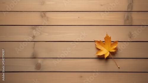 Single yellow autumn leaf resting on horizontal wooden planks
