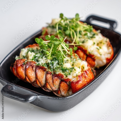 Delicious baked lobster tail with melted cheese and fresh microgreens served in a small black dish on a white surface perfect for seafood cuisine and gourmet dining