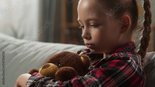 Portrait pensive sad Caucasian child girl hugging toy Teddy Bear at couch offended frustrated lonely kid daughter thinking problem trouble bad mood at home stress custody adoption family abuse sorrow