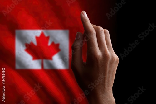 A darkskinned hand is raised against a blurred backdrop of the Canadian flag