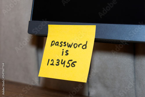 A bright yellow sticky note shows a password on a computer screen