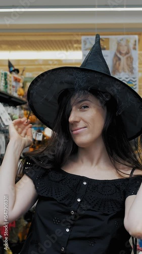 Halloween witch. Halloween party. witch costume. shopping Halloween accessories. in the store, a beautiful brunette woman is trying on a black witch hat for a Halloween party.