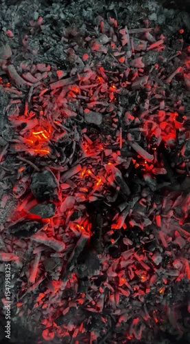 Close-up of glowing hot embers and ash with smoldering wood, capturing the intense heat and texture of a dying fire.