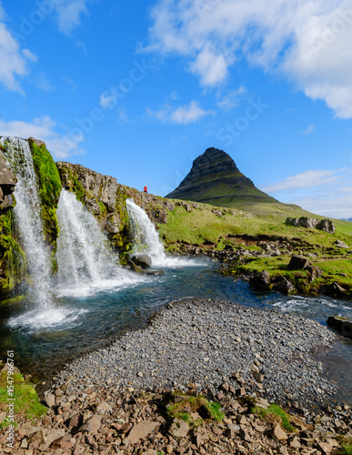 Majestic waterfalls cascading beside Kirkjufell mountain in Iceland under a bright blue sky