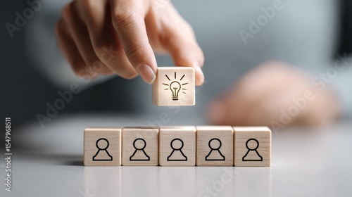 Person is holding a cube with a light bulb on it and placing it on top of a stack of other cubes. Concept of innovation and creativity, as the light bulb represents a new idea or solution