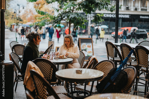 Принти на полотні Two people share a meal at an outdoor cafe, surrounded by an urban and rainy ambiance