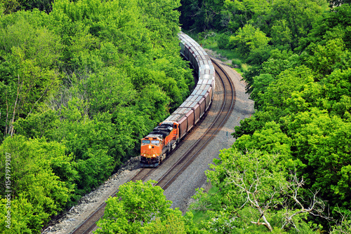 Diesel locomotive coming around a curve pulling a freight train comprised of grain cars