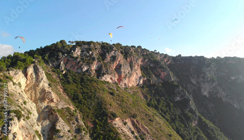 Aerial View of Paragliders Soaring Over Scenic Cliffside on a Sunny Day photo