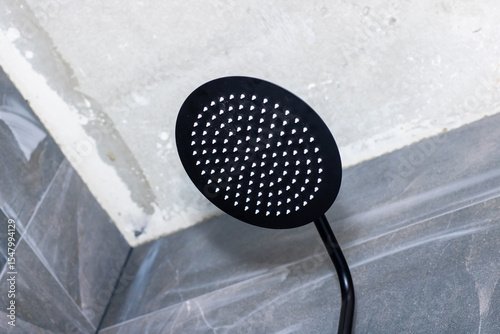 A black shower head that has white dots adorning its surface