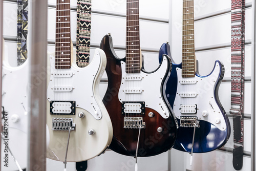 Many electric guitars hanging on wall of music shop, close up.