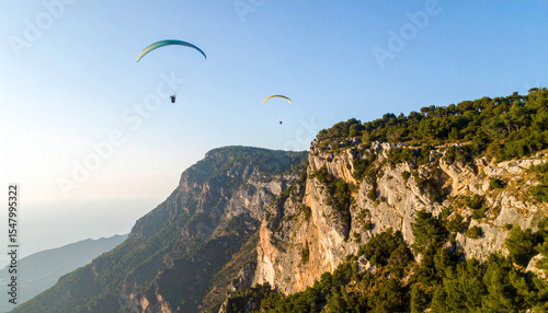Aerial View of Paragliders Soaring Over Scenic Cliffside on a Sunny Day photo