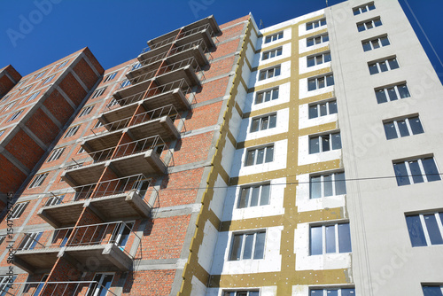Apartment building during construction made of brick, as well as external thermal insulation with glass wool and styrofoam insulation