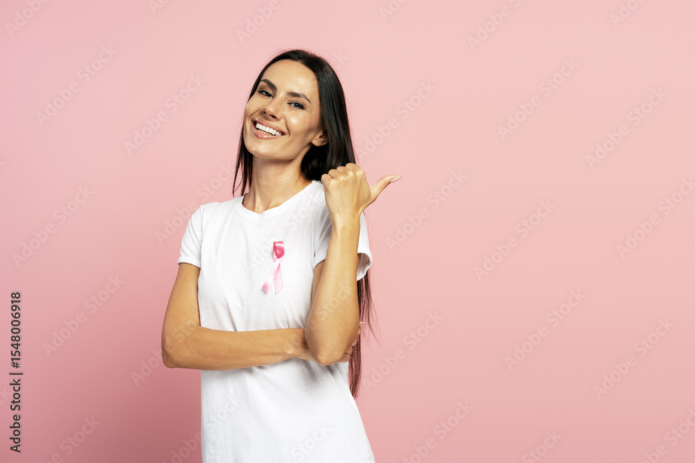 Woman pointing aside while showing pink ribbon for breast cancer awareness Woman pointing aside while showing pink ribbon for breast cancer awareness