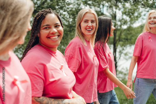 Foto Diverse women walking together showing pink ribbons for breast cancer awareness