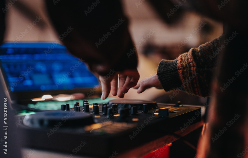 Fototapeta premium Two individuals collaborate on a DJ setup, showcasing teamwork and passion for music creation.