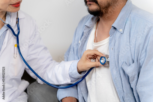Physician listening to patient’s breath sounds with stethoscope during routine health checkup.