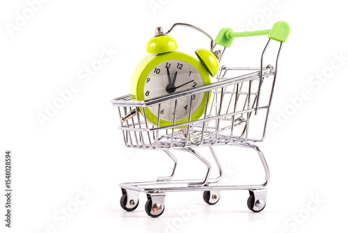 Alarm clock in miniature supermarket shopping trolley on white background