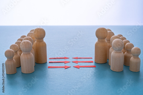Concept of conflict I war between people or groups. Wooden figures gathered in two groups facing each other.