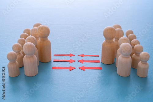 Concept of conflict I war between people or groups. Wooden figures gathered in two groups facing each other.