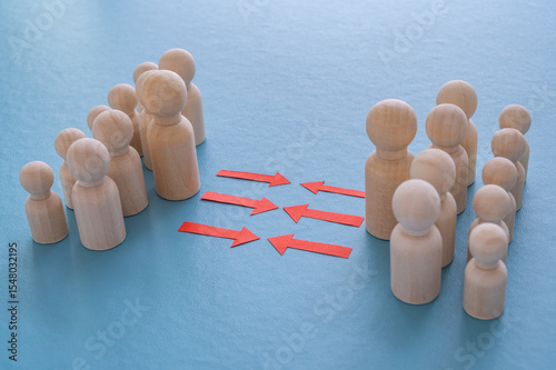 Concept of conflict I war between people or groups. Wooden figures gathered in two groups facing each other.