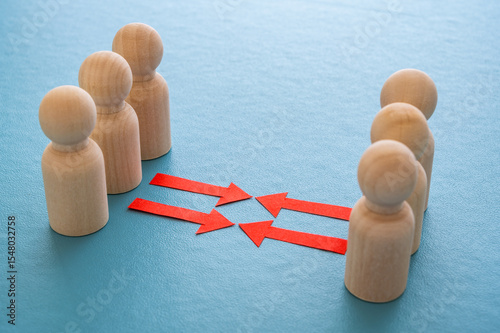 Concept of conflict I war between people or groups. Wooden figures gathered in two groups facing each other.