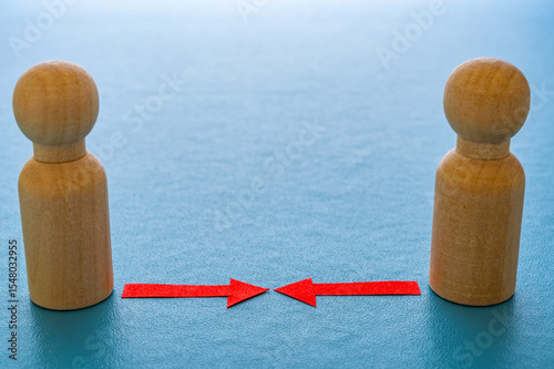 Concept of conflict I war between people or groups. Wooden figures gathered in two groups facing each other.