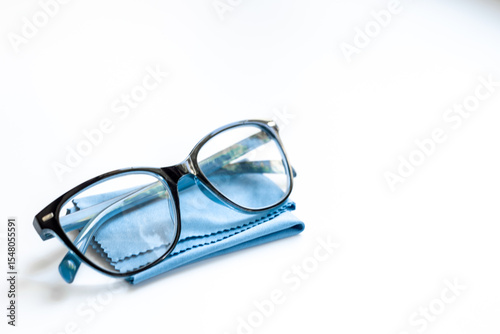 Stylish eyeglasses with glasses cloth on white. Eye care and protection concept