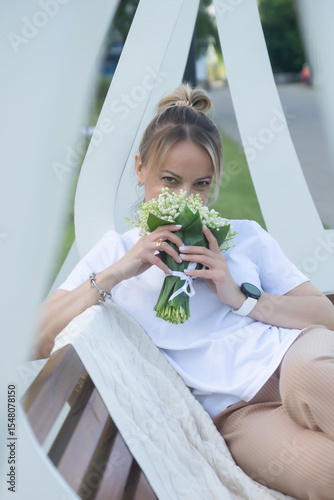 A young, beautiful girl with a bouquet of lilies of the valley on a walk.